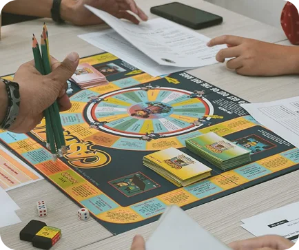 Mensen die een educatief bordspel spelen met kaarten, dobbelstenen en werkbladen, waarbij plezier en leren worden gecombineerd